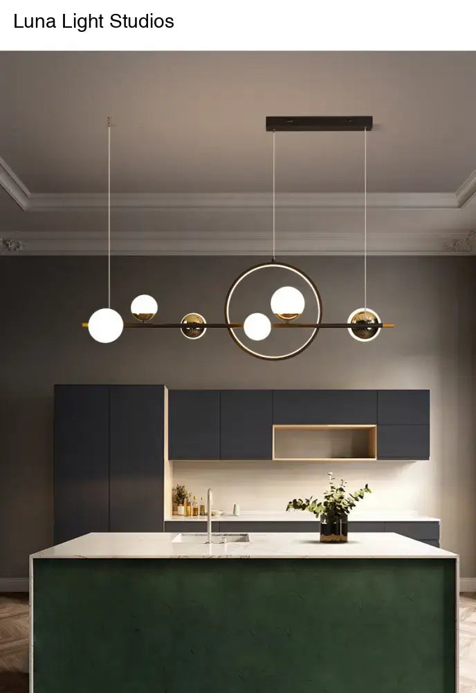Modern black metal pendant light with spherical white glass bulbs and gold-toned accents for dining room use