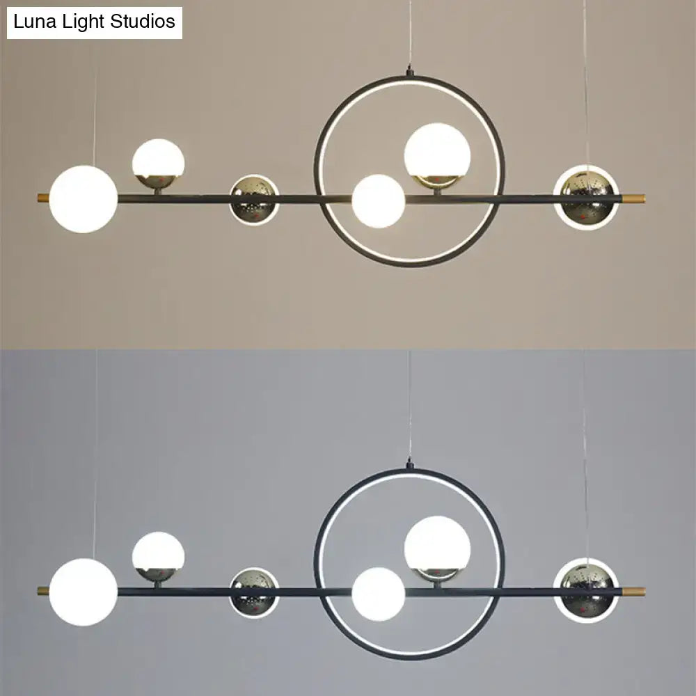 Modern black metal pendant light with brass geometric frame and spherical glass bulbs for dining room lighting