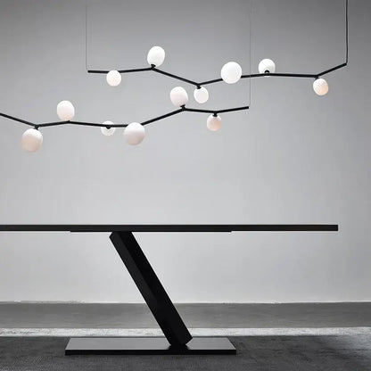 Modern black minimalist glass branch chandelier above a sleek black metal table with angular base for dining room decorbites glass branch