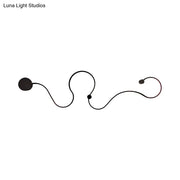 Modern black minimalist wall lamp with sleek curved lines and spherical accents emitting white light for living room use
