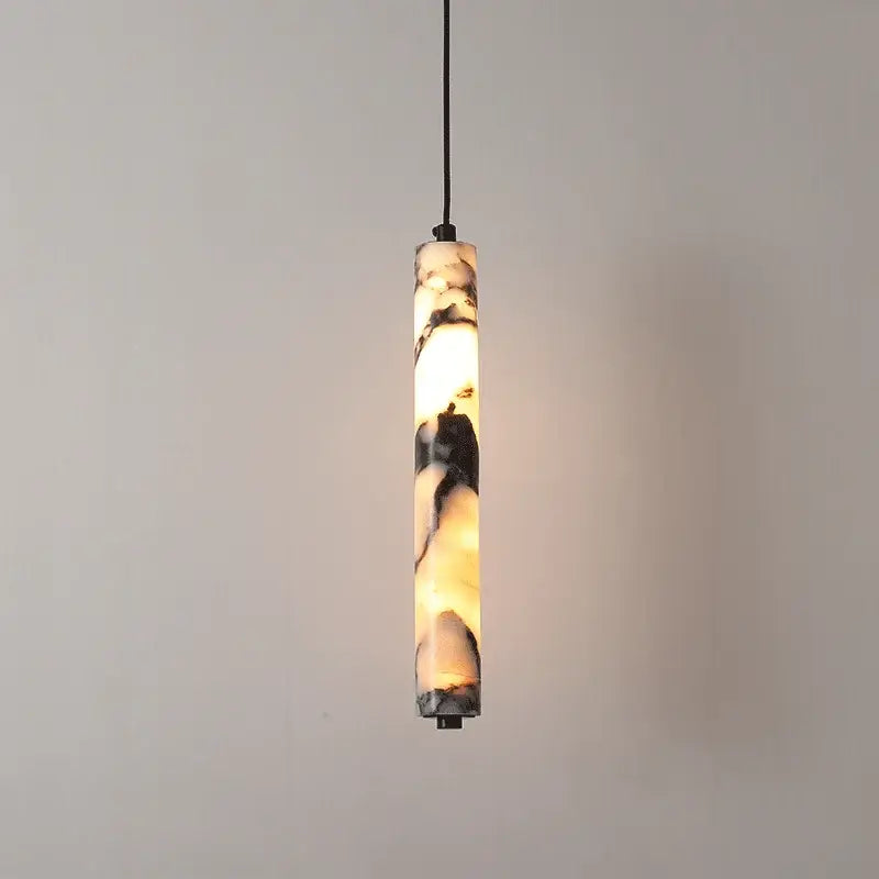 Modern black natural marble stone cylinder pendant light with warm glowing interior and swirling cream black gray patterns