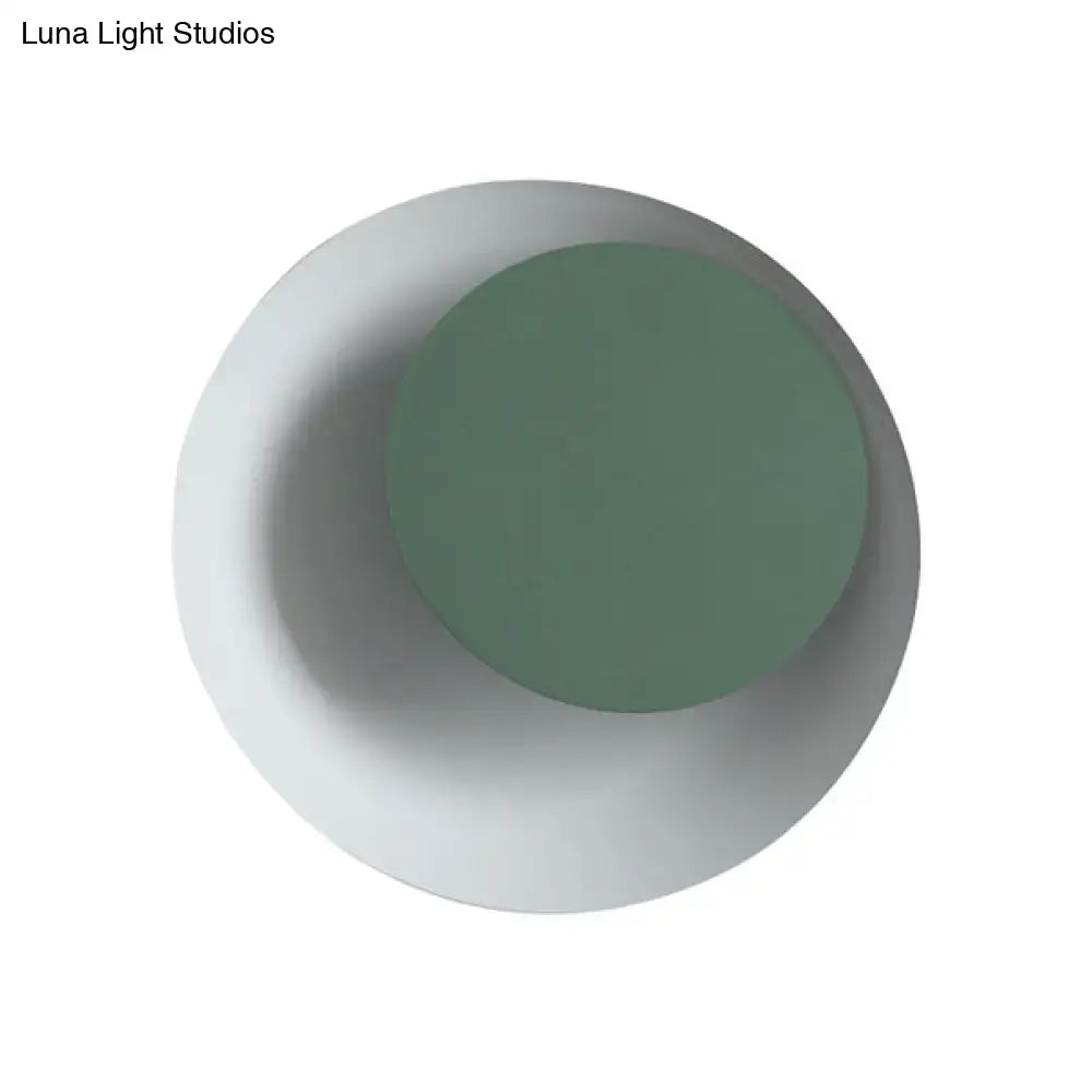 Modern black and pink circle sconce light fixture with a minimalist matte sage green center and off-white outer ring