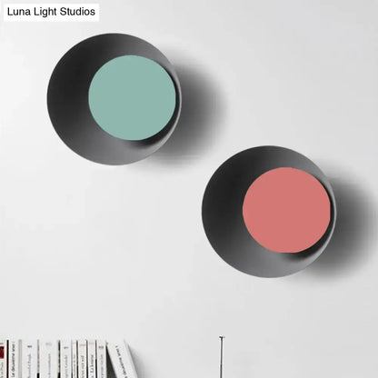 Modern black and pink circle sconce light fixture with matte black exterior and muted teal and soft coral interiors