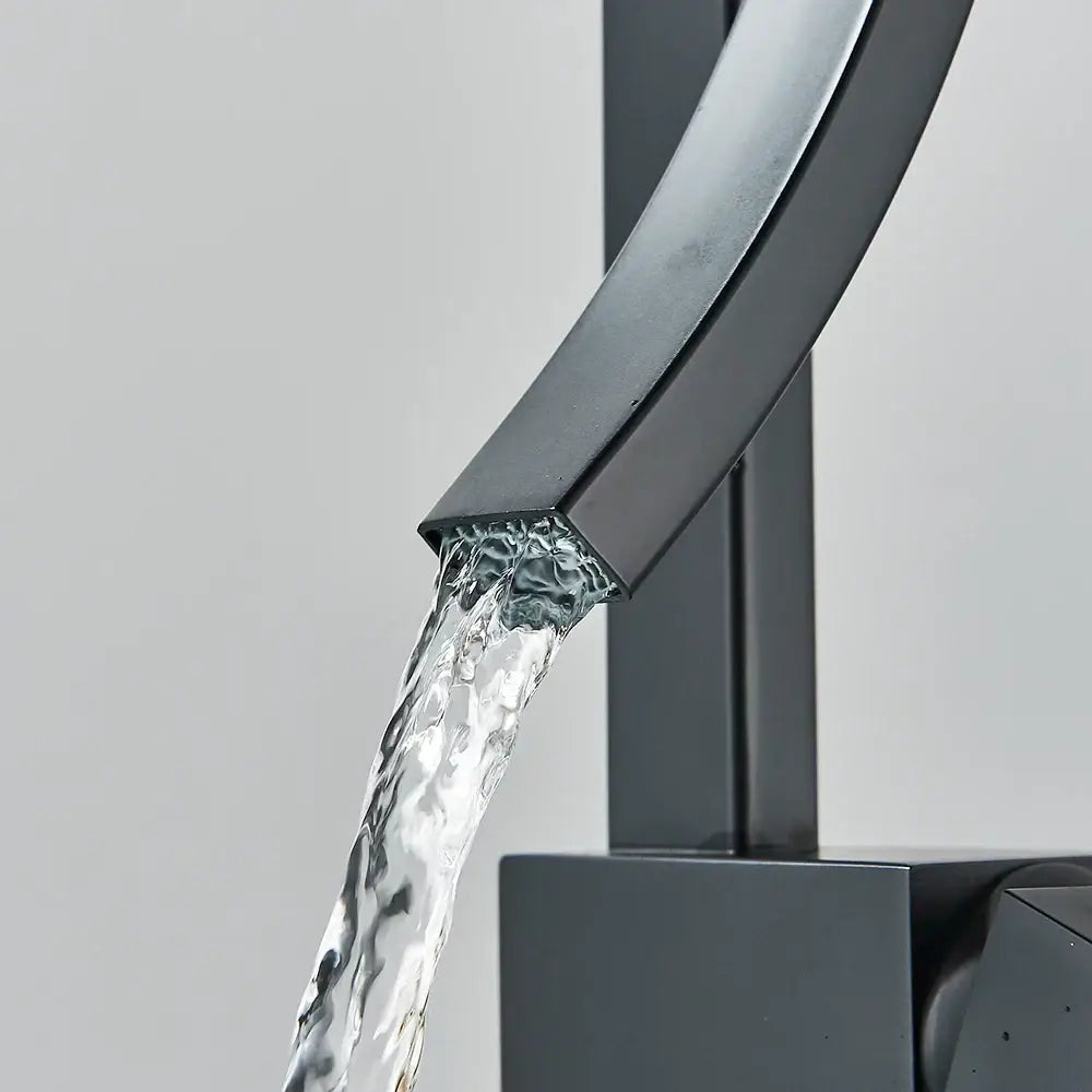 Modern black quartz waterfall basin faucet with single handle mixer tap and sleek matte black curved spout flowing water