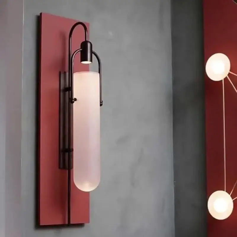 A sleek black metal wall lamp with frosted glass shade led and red rectangular backplate for bedroom sconce