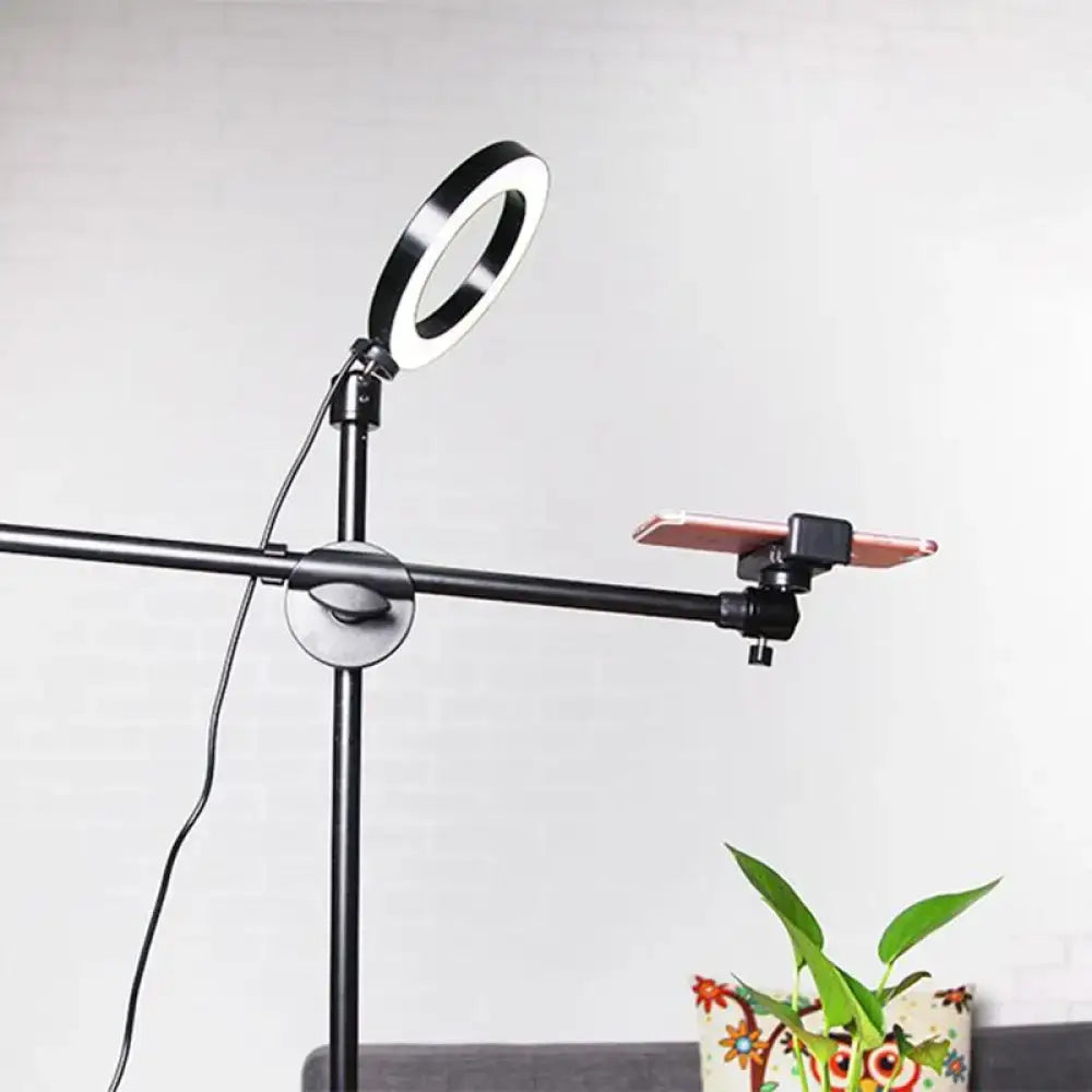 Black round led vanity lamp with adjustable arm and phone holder mounted on a stand for bedroom lighting