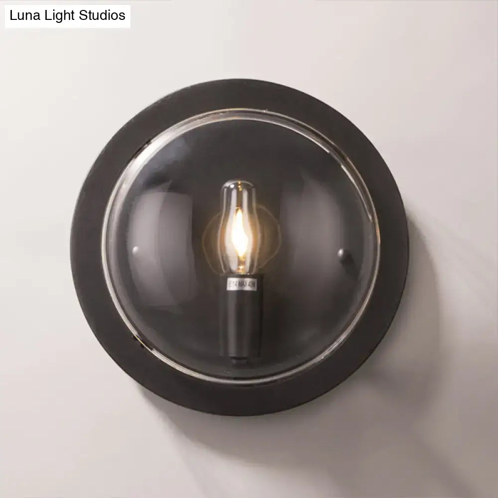 Modern black round wall sconce with clear glass dome housing an exposed filament e12 bulb for hallway lighting