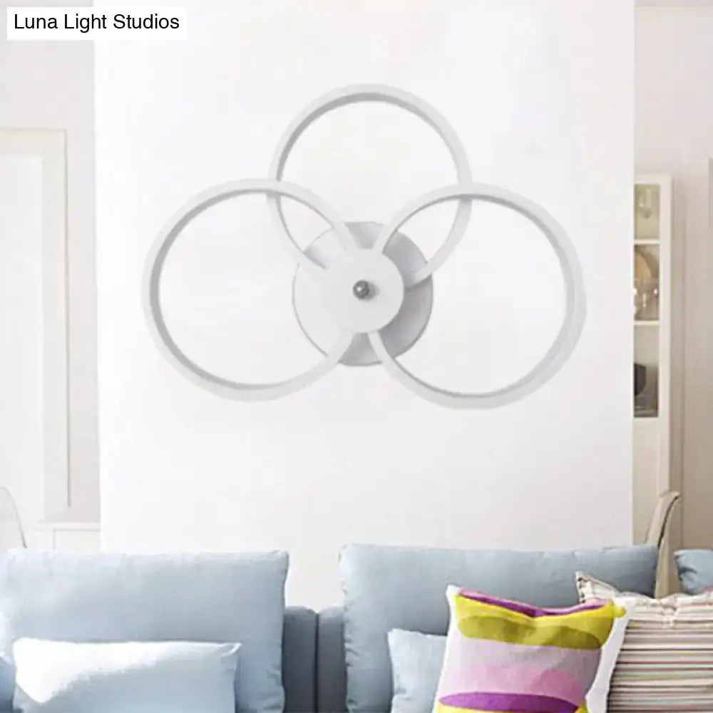 Modern white circular wall lamp with three interlocking rings and central metallic accent for bedroom lighting