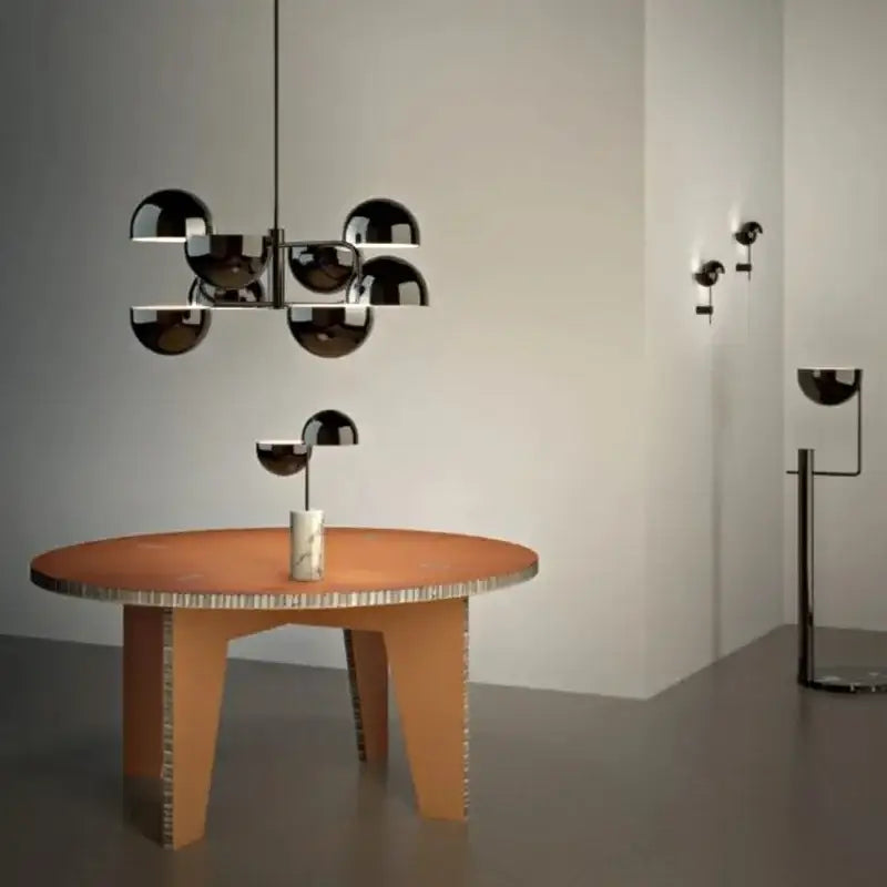 Modern black spherical abstract art chandelier with pendant lamp design above terracotta textured table with cardboard legs