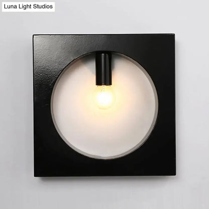 Black square wall sconce lamp with circular frosted glass diffuser and exposed bulb for modern bathroom lighting
