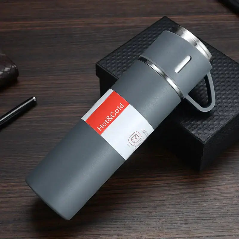 Gray insulated water bottle with stainless steel lid handle and red white hot and cold label vacuum insulated water