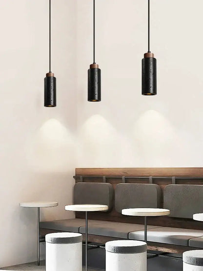 Modern black stone bedside chandelier featuring three sleek black cylindrical pendant lights with copper accents