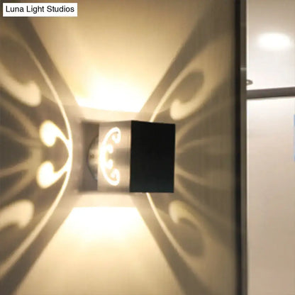 Modern black led wall lamp with ornate swirl design casting warm light patterns for bedroom use