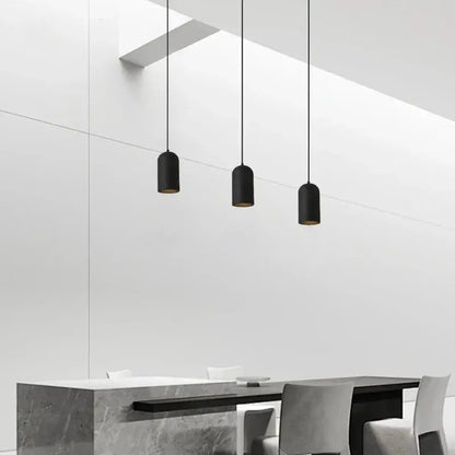 Three sleek black travertine led pendant lamps with gold interior lining hang from ceiling in modern kitchen decorbites style