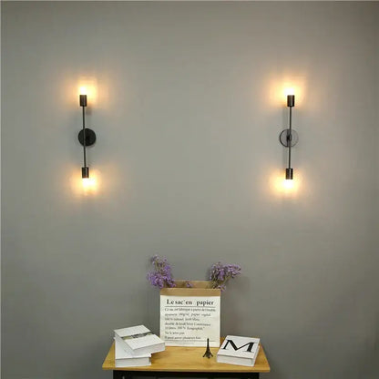 Pair of modern black led wall lamps with cylindrical shades and circular backplates for bedroom vanity lighting
