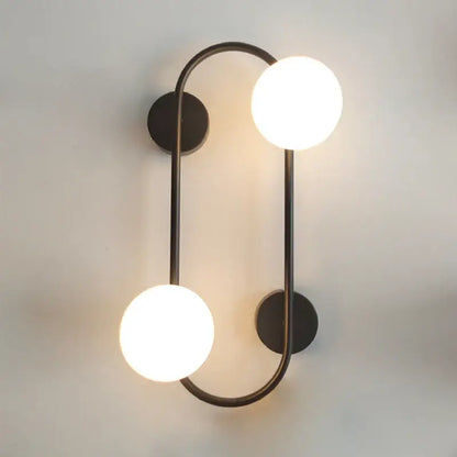 Modern black wall sconce with frosted glass globes featuring two glowing bulbs for bedroom decorbites brass led style