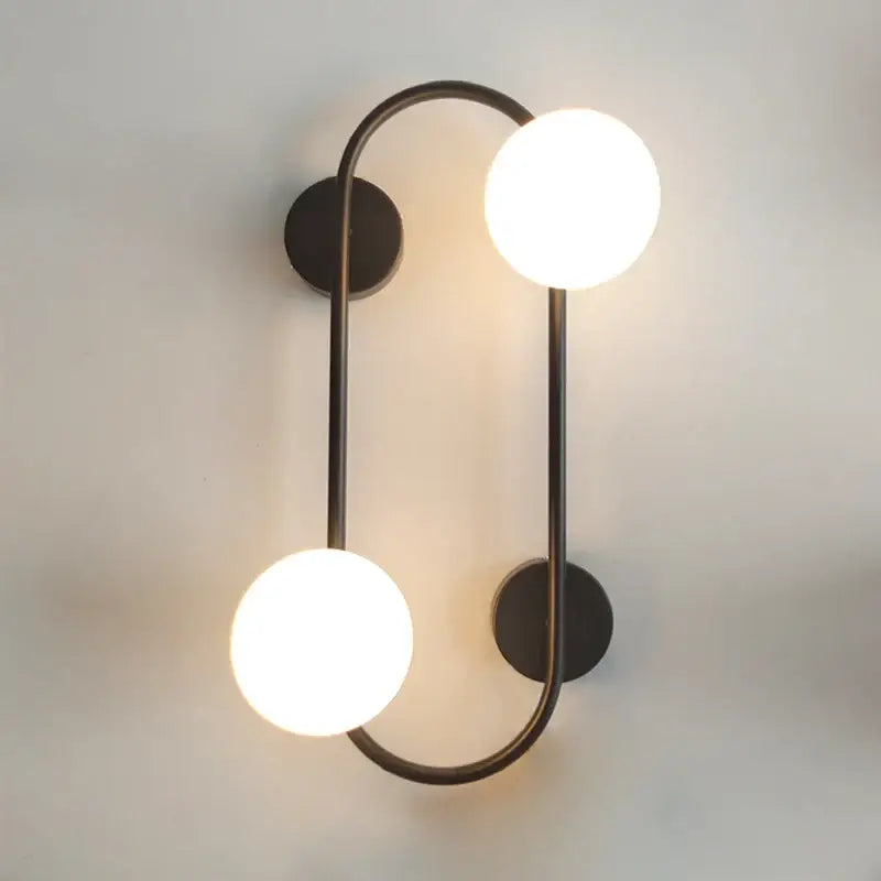 Modern black wall sconce with frosted glass globes featuring two glowing white spherical bulbs for bedroom decorbites brass led use