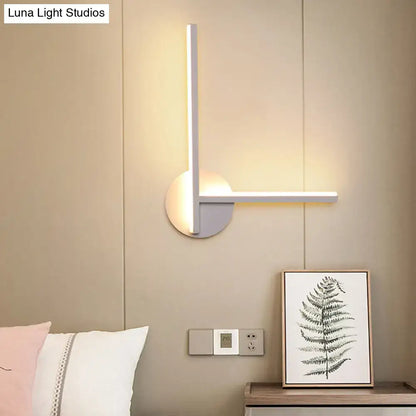 Modern black and white acrylic cross wall sconce with sleek vertical arm emitting warm white light for bedroom use
