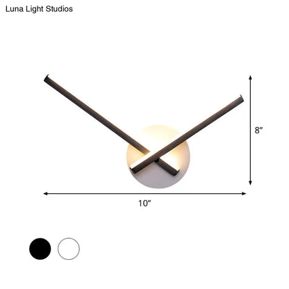 Modern black and white acrylic cross wall sconce with two intersecting arms emitting warm white light for bedroom use
