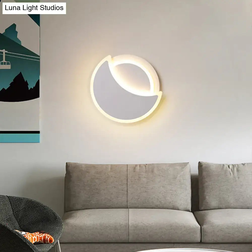 Modern black and white acrylic eclipse wall sconce with crescent shape and soft glowing light for bedroom use