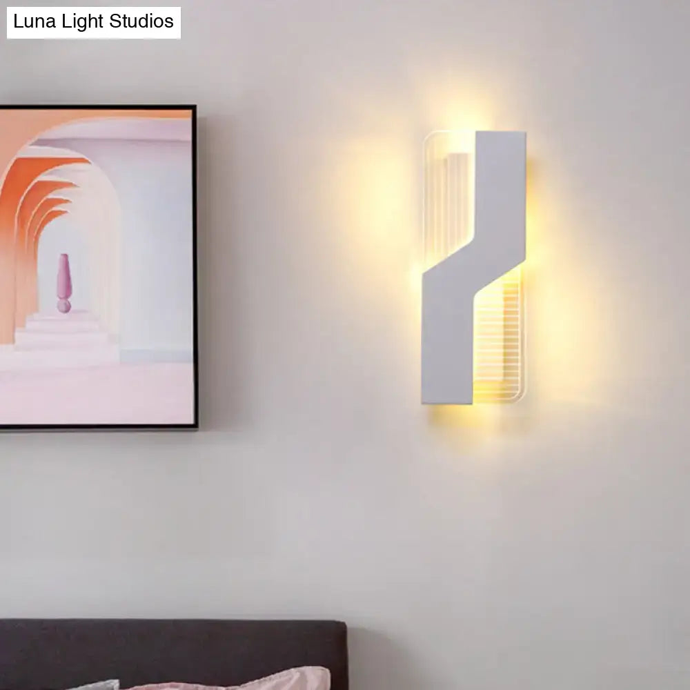 Modern white angular wall mount light with vertical slatted panel emitting warm yellow light for bedroom use