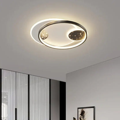 Modern black decorbites living lamp chandelier with circular black metal frame and glowing starry celestial discs for dining room