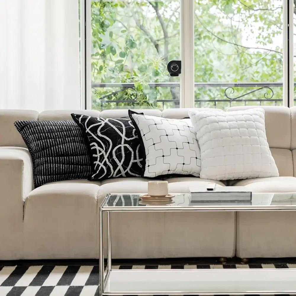 Beige upholstered sofa with four black and white decorbites geometric jacquard cushion covers for living room decor