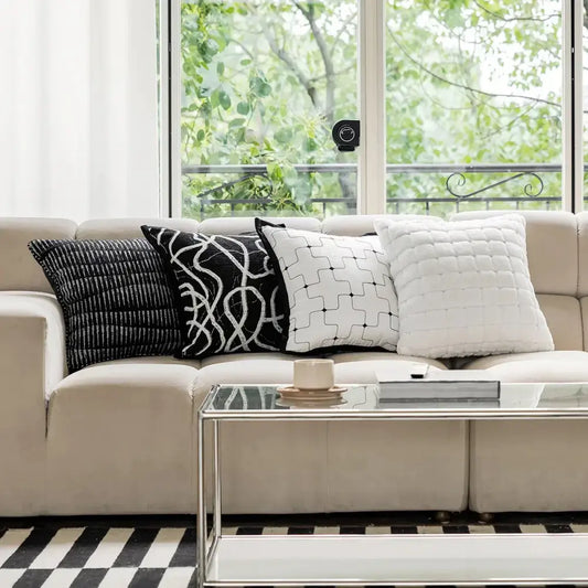 Beige upholstered sofa with four black and white decorbites geometric jacquard cushion covers for living room decor