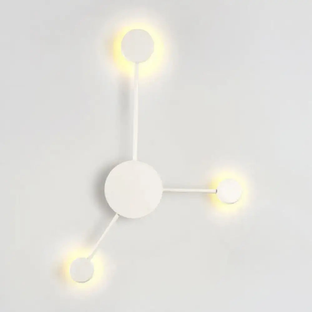 Minimalist white wall sconce with three glowing circular lights in a modern black and white geometric light fixture design