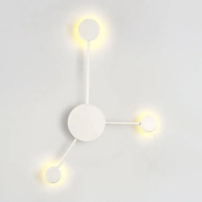 Minimalist white wall sconce with three glowing circular lights in a modern black and white geometric light fixture design