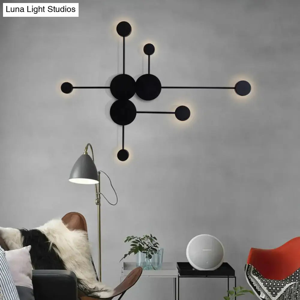 Modern black wall sconce with circular elements and glowing lights serving as a geometric living room wall light fixture