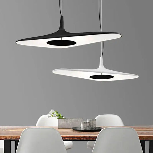 Modern black and white decorbites irregular pendant light with sleek disc-shaped design hanging above dining table