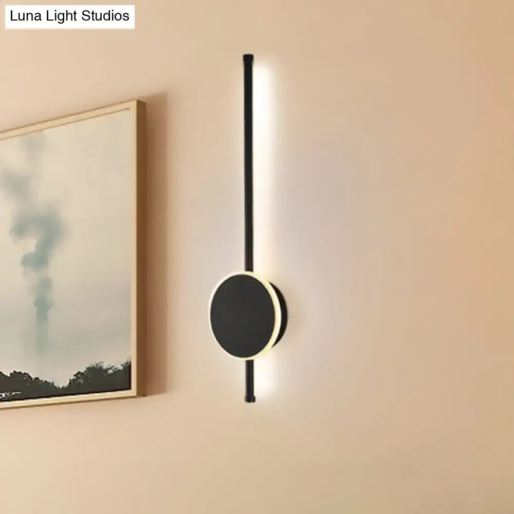 Modern black and white led wall sconce with sleek vertical rod and circular base featuring warm color temperature lighting