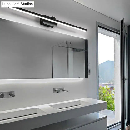 Modern black white linear light fixture bathroom wall sconce mounted above a sleek white vanity mirror