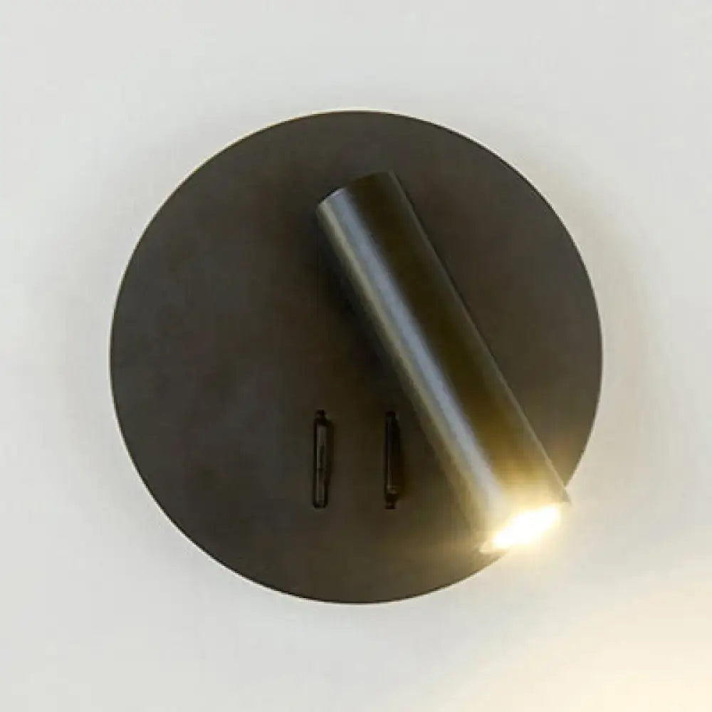 Modern black and white metal wall lamp with circular design and cylindrical head emitting warm illumination for living room use