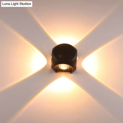 Modern black cylindrical mini cube wall lamp with warm golden beams mounted in living room sconce