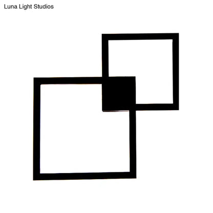 Modern black geometric wall sconce with acrylic shade featuring overlapping squares for dining room use