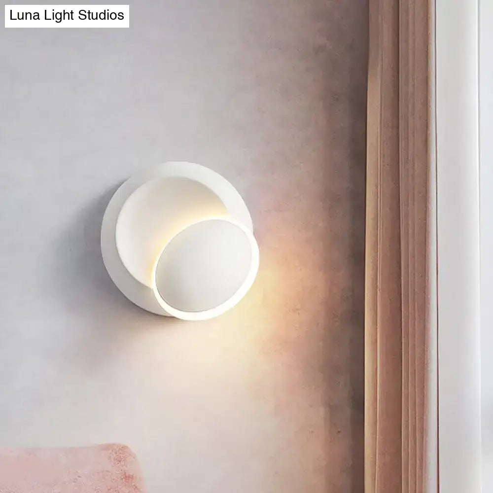 Modern black and white rotating eclipse wall lamp with a sleek white rotating circular sconce emitting warm light