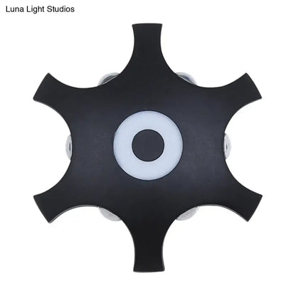 Modern black star-shaped ceiling light fixture with white ring and silver bulb housings providing warm white light