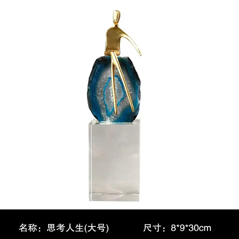 A sleek gold crystal golden sculpture on blue and white agate crystal slice on clear acrylic base for living room decorbites decor