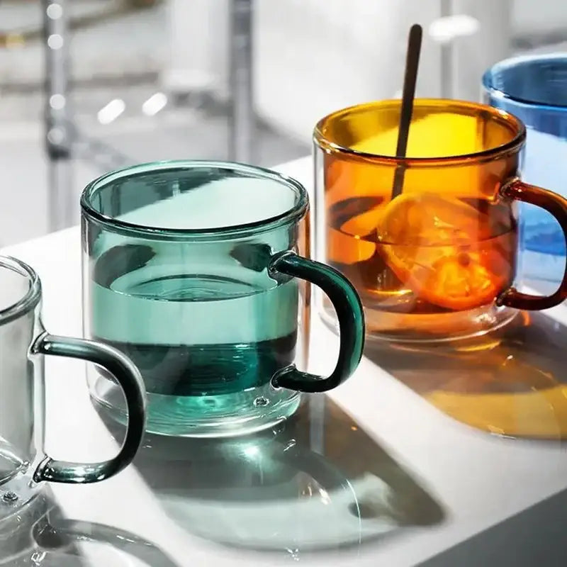 Clear glass mugs set with modern teal and amber translucent handles for dining room use