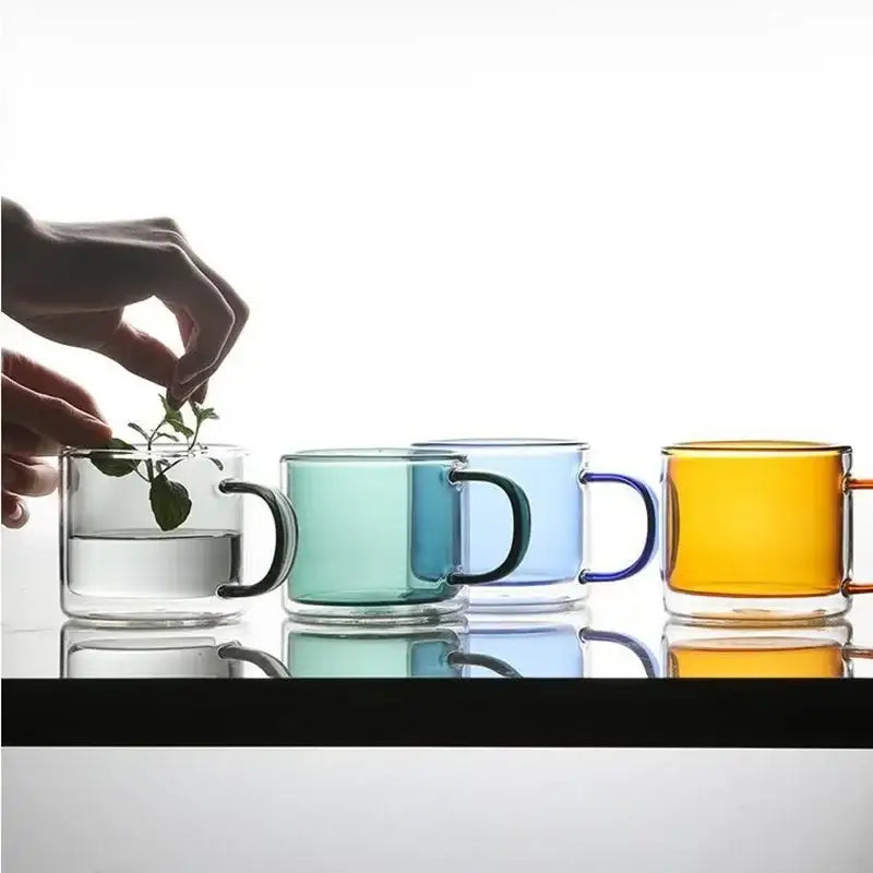 Set of four translucent glass mugs in blue amber teal and clear hues with matching handles glass mugs set for dining room