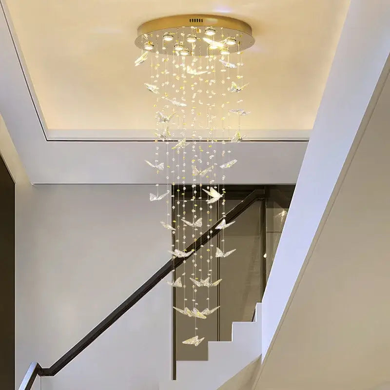 A modern decorbites butterfly crystal chandelier with gold base clear crystals and white butterfly ornaments for staircases
