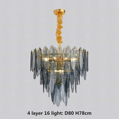 A modern pendant light with four tiers of translucent gray glass leaves on a decorbites gold metal chain