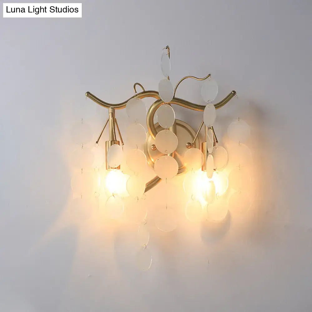 Gold-toned wall lamp with branch design featuring curved metal arms and translucent white discs for bedroom sconce decor