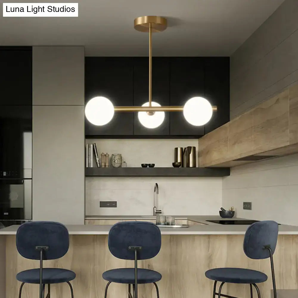 Modern brass pendant light with three spherical glass shades designed for dining room illumination