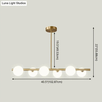 Modern brass 5-light pendant light with spherical glass shade featuring five frosted globe bulbs in a linear design
