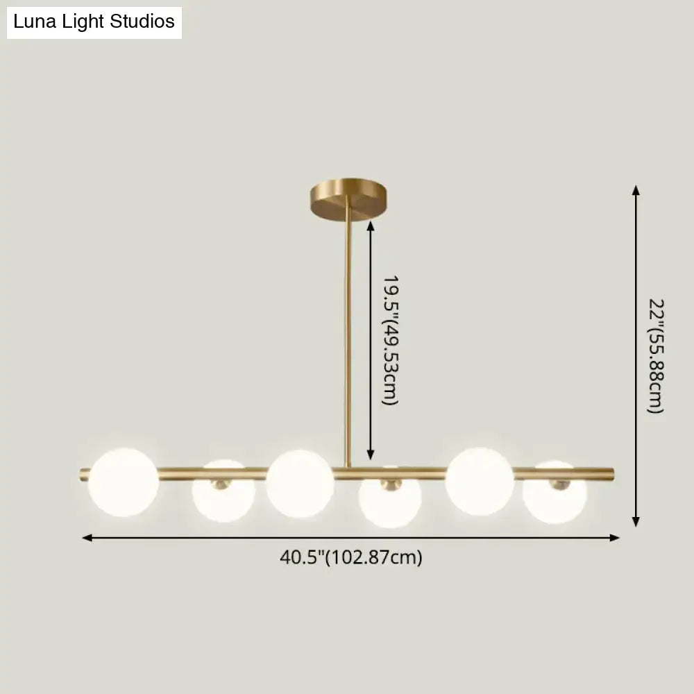 Modern brass 5-light pendant light with spherical glass shade featuring five frosted glass globes in a linear design