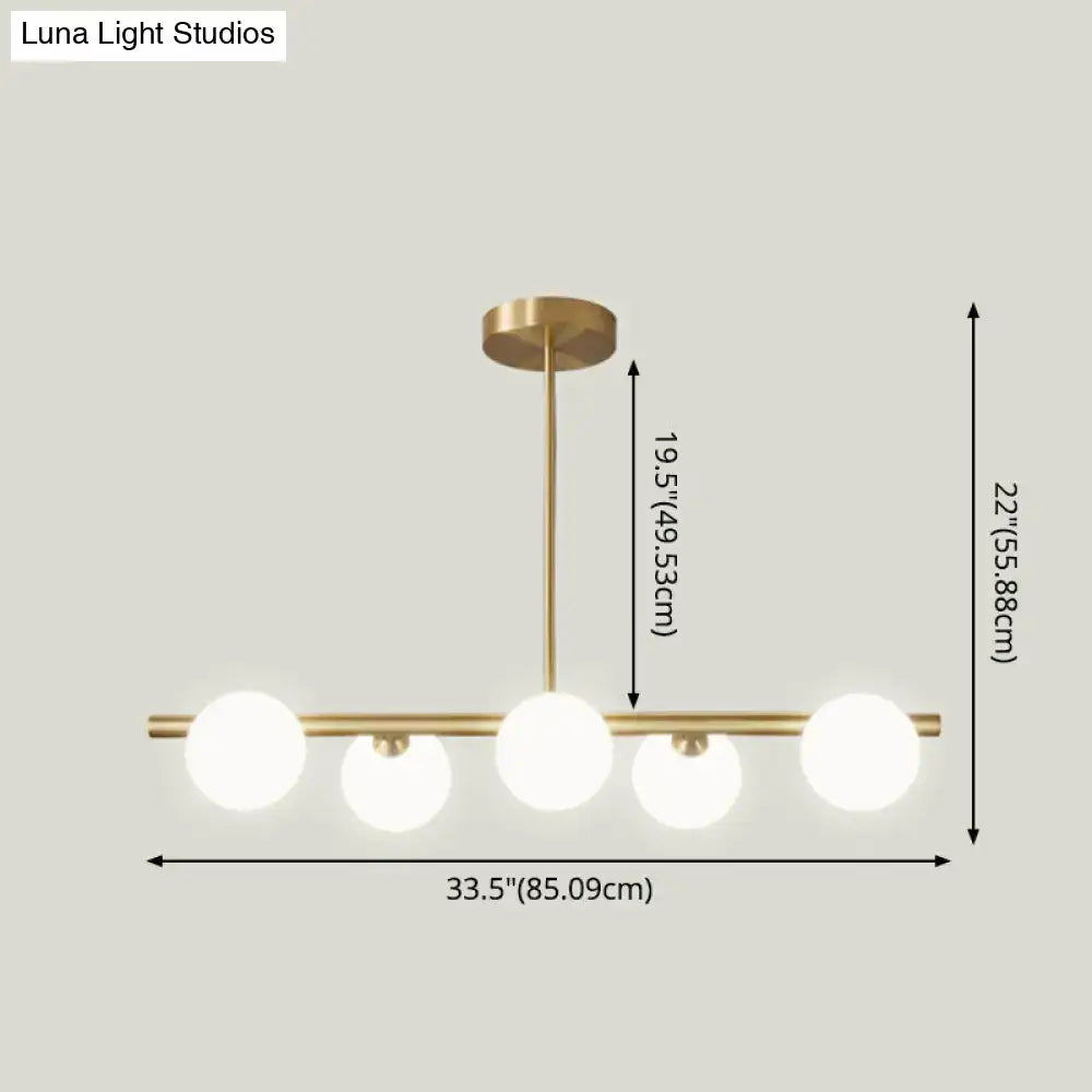 Modern brass 5-light pendant light with spherical glass shade and frosted bulbs for dining room lighting