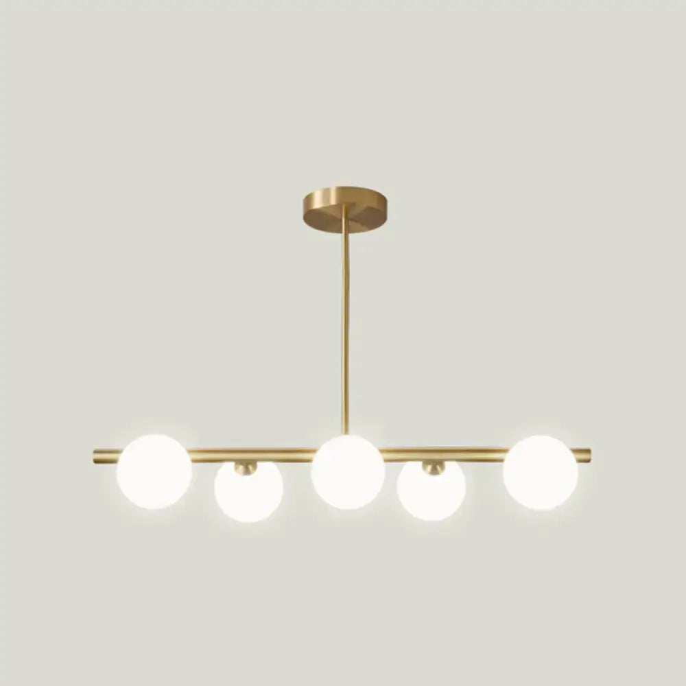 Modern brass 5-light pendant light with spherical glass shade featuring frosted glass globes in linear design